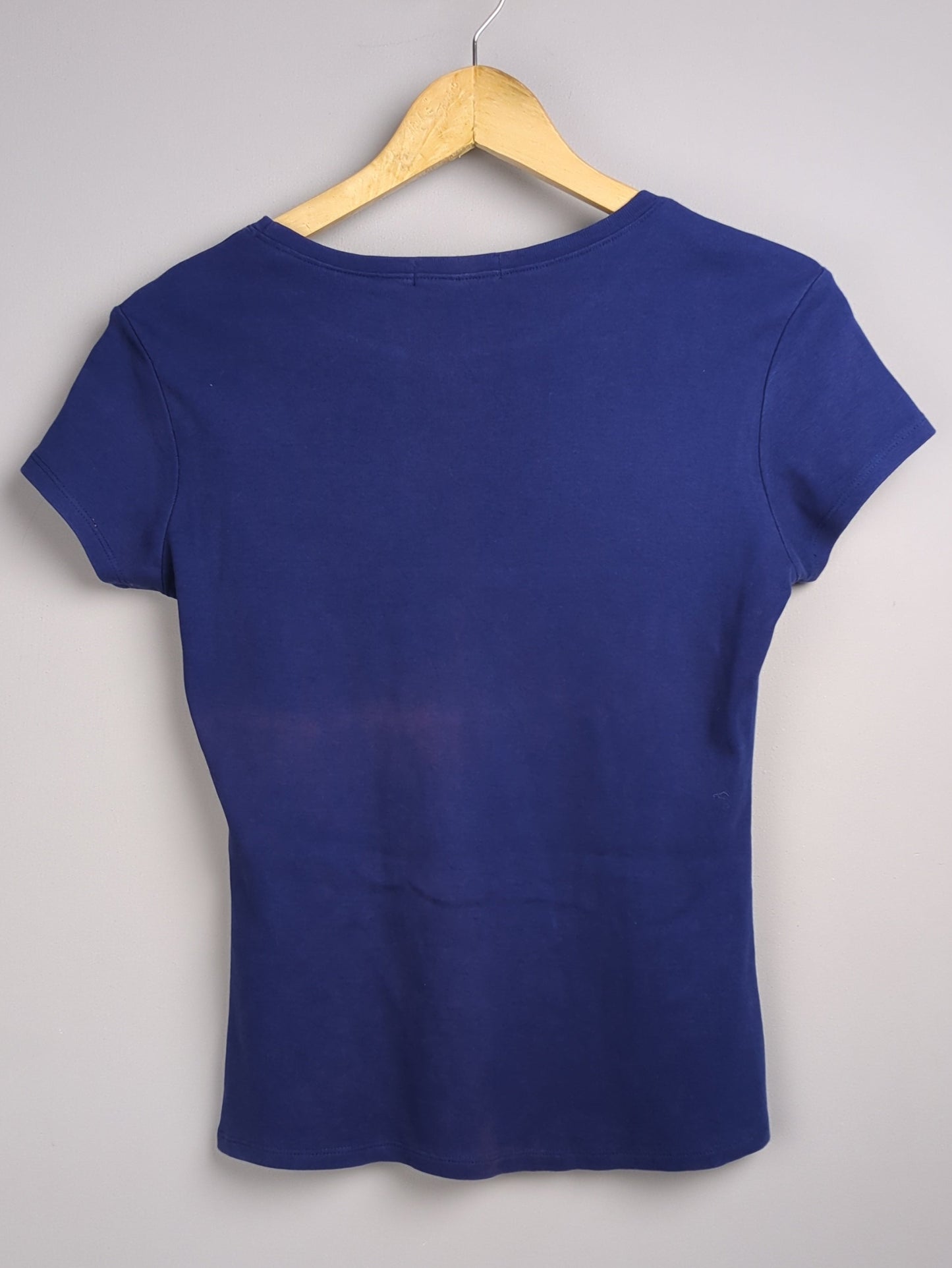 Blue top on a hanger against a gray background