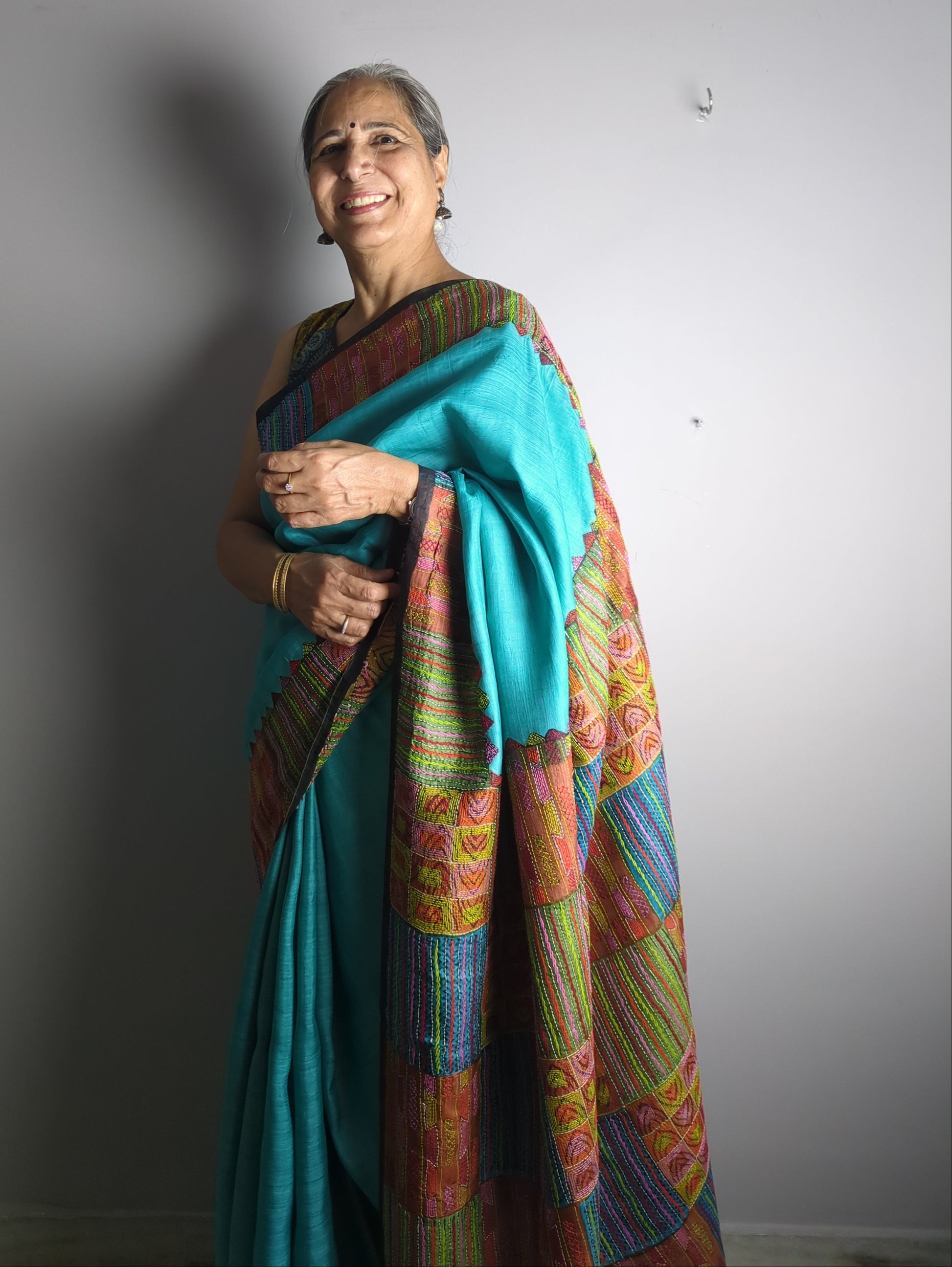 Person wearing a colorful saree with a plain background