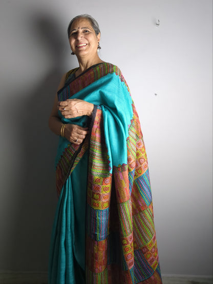 Person wearing a colorful saree with a plain background
