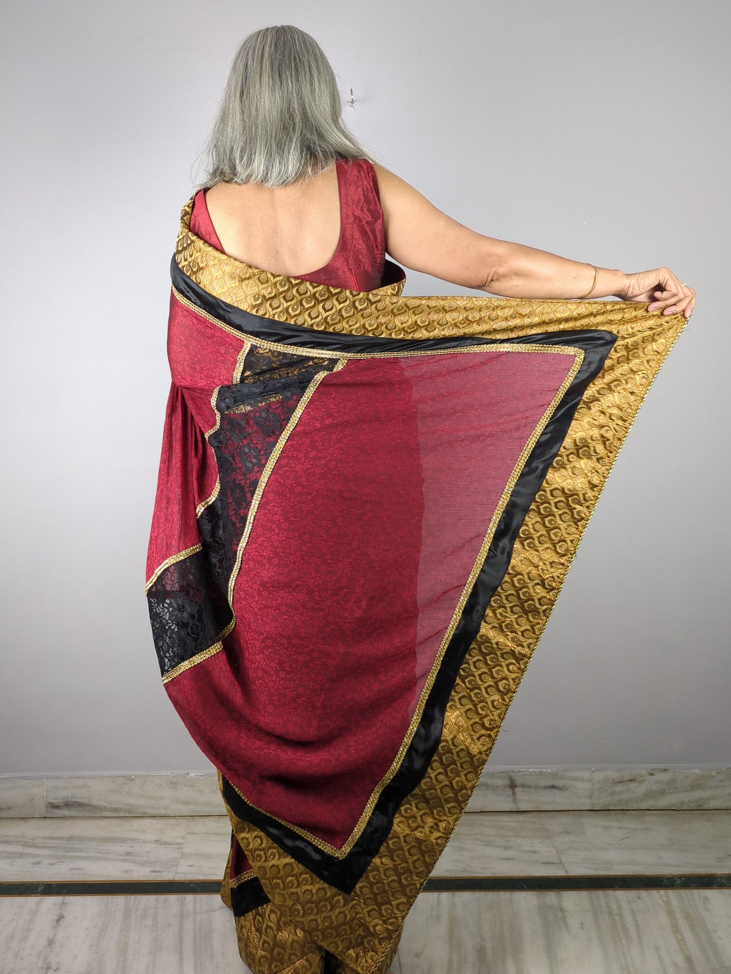 Person holding a red and gold traditional garment against a plain background