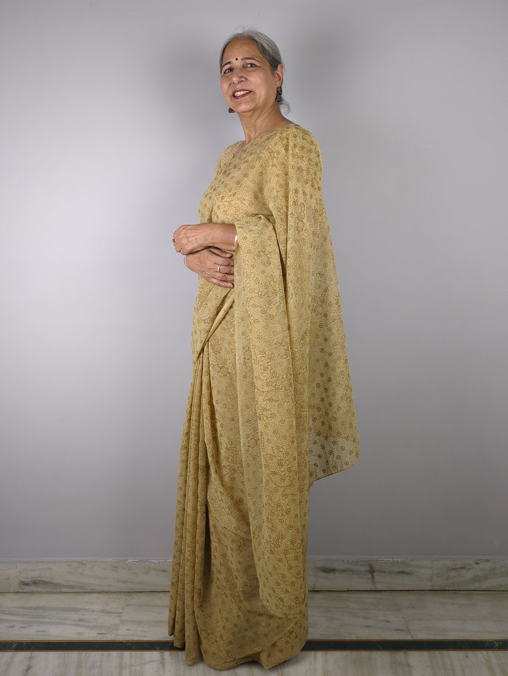 Person wearing a yellow traditional outfit against a plain background