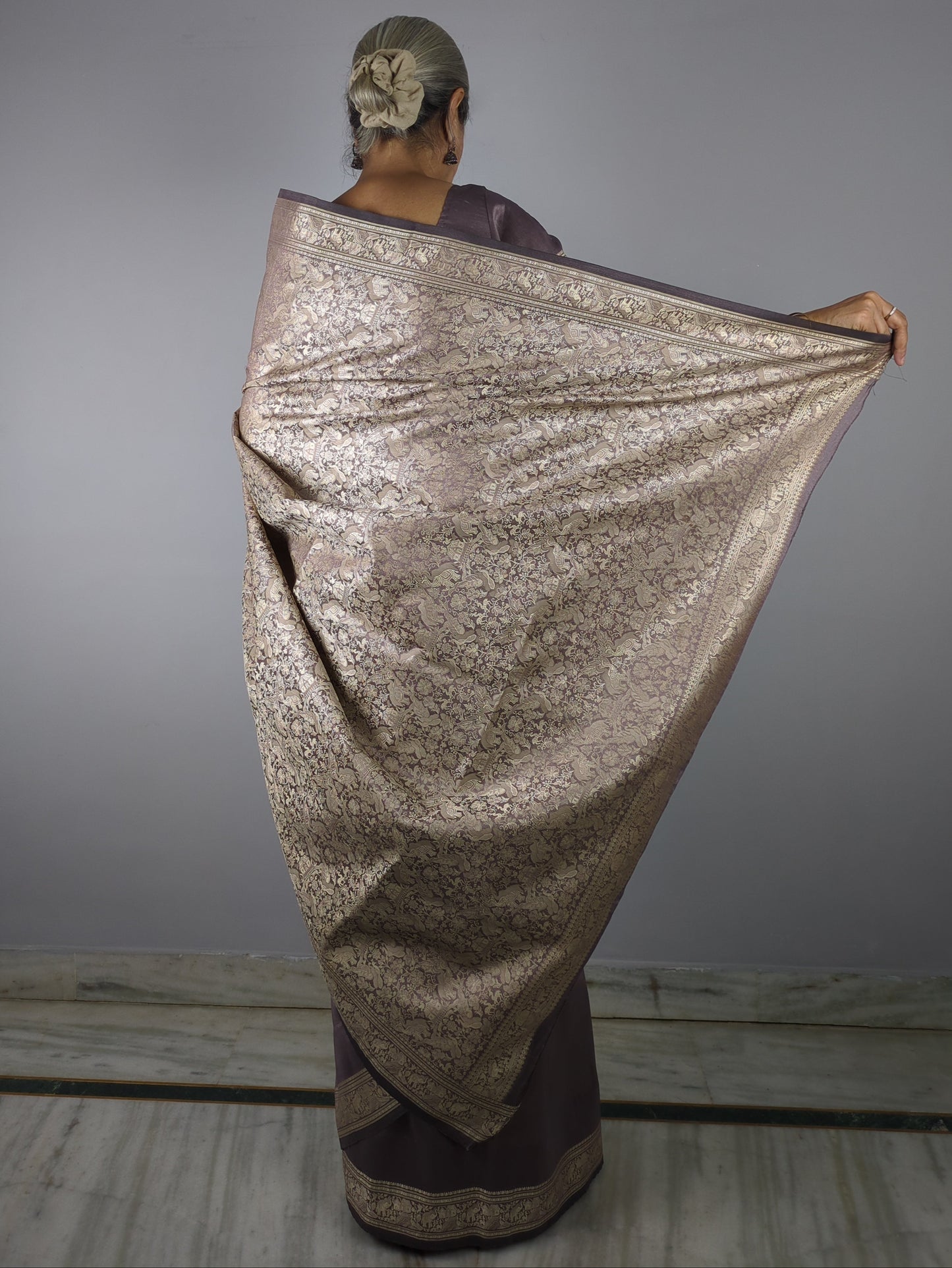 Person wearing a glittery silver dress against a gray background