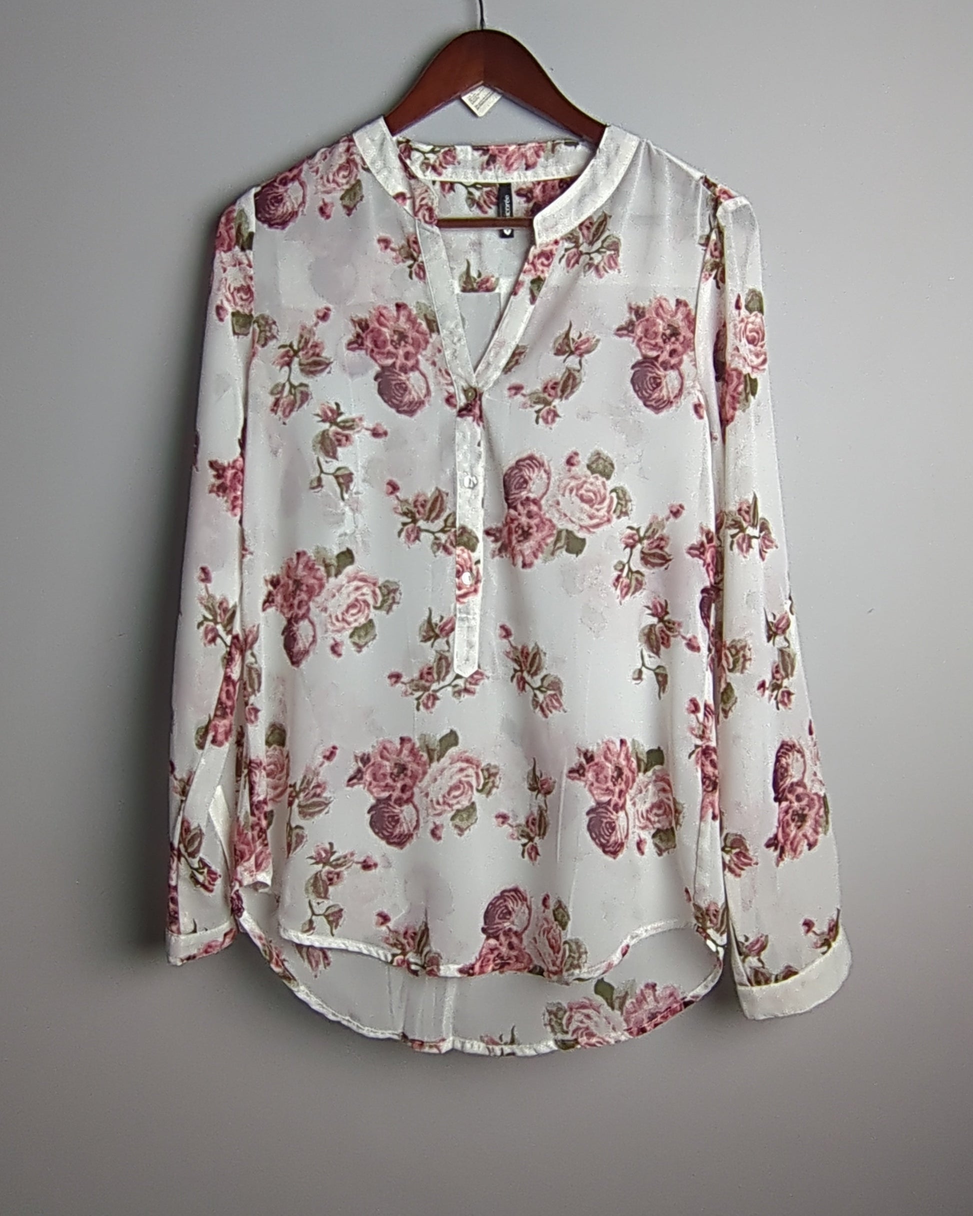 Floral blouse on a hanger against a gray background
