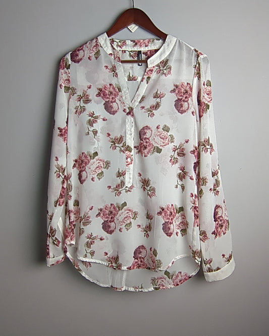 Floral blouse on a hanger against a gray background