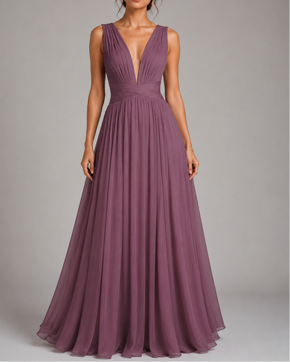 A sleeveless, floor-length plum purple gown with a deep V-neckline and pleated skirt, shown on a model against a neutral gray studio background.