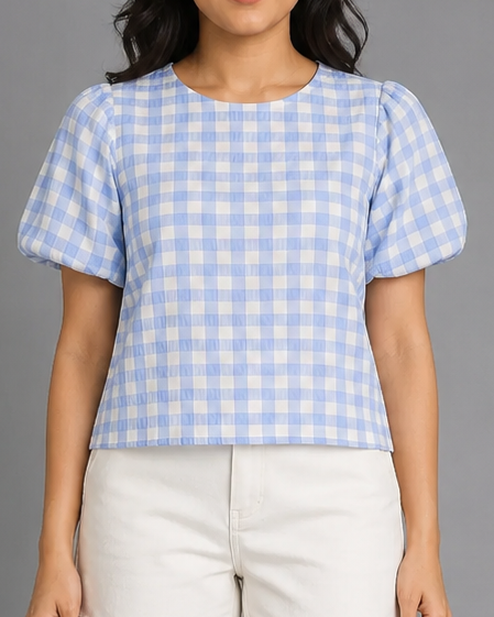 Woman wearing a blue and white checkered top with white shorts on a gray background