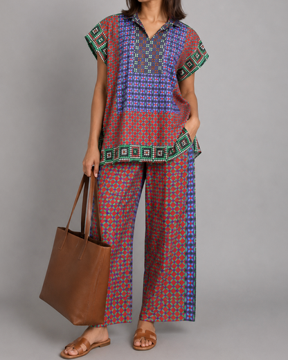 Woman wearing a patterned outfit holding a brown bag against a gray background