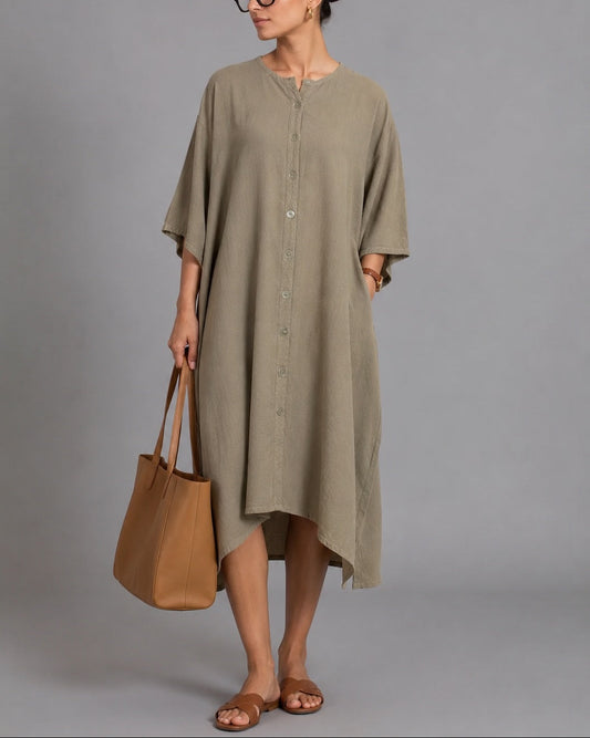 Woman wearing a long olive green dress holding a brown bag against a gray background