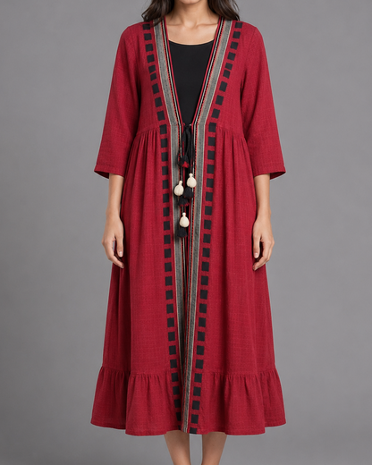 Woman wearing a red dress with black embroidery on a gray background