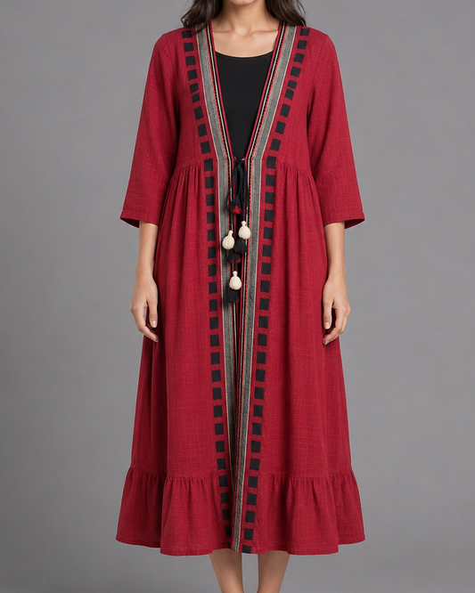 Woman wearing a red dress with black embroidery on a gray background