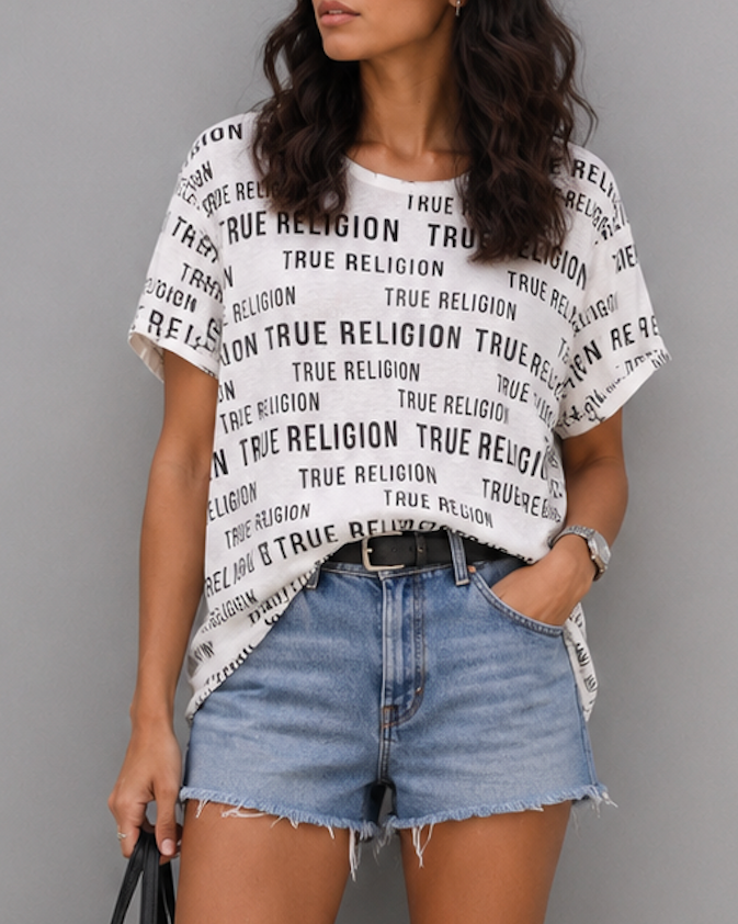 Woman wearing a True Religion t-shirt, denim shorts, and white sneakers on a gray background
