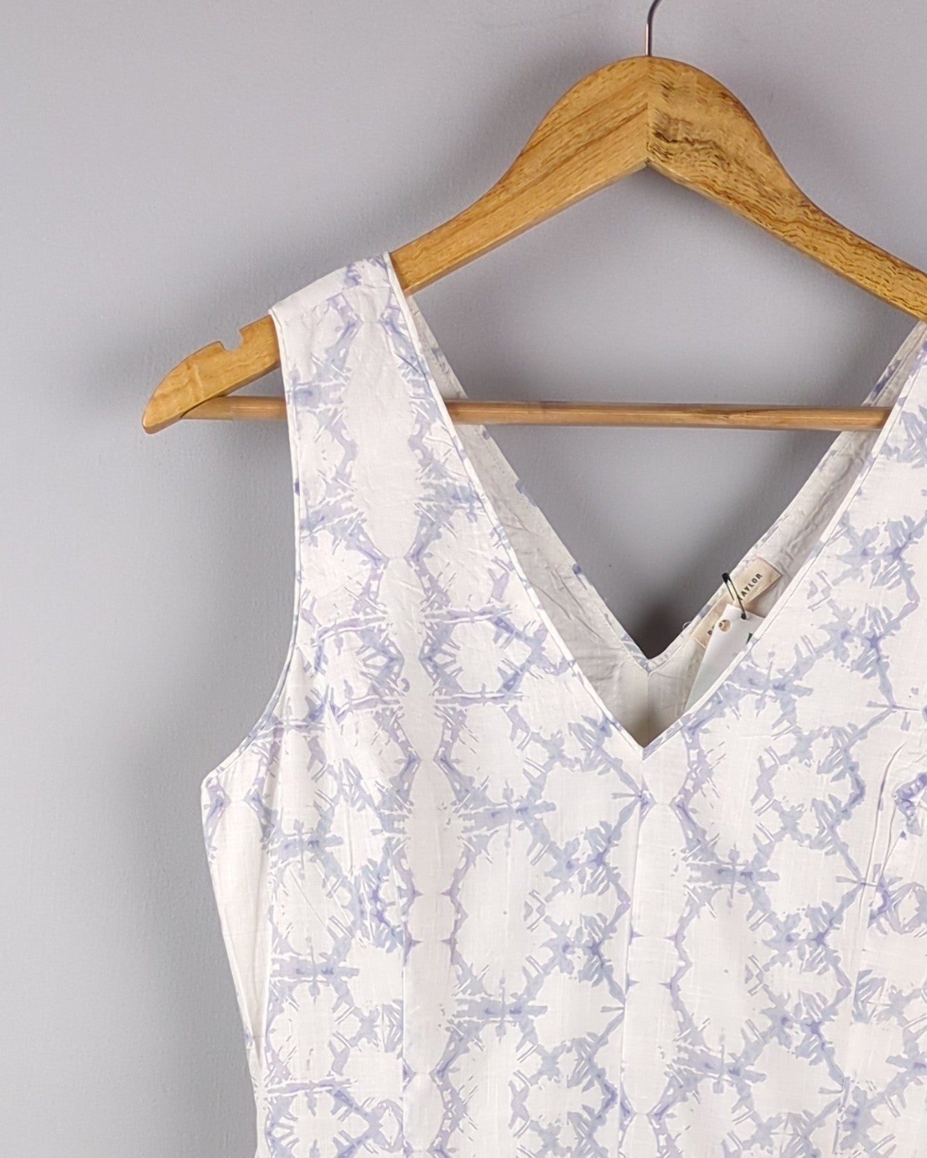 Delicate cotton dress made with Shibori style light indigo dye. The dress has a feminine silhouette and shows the top left of the dress